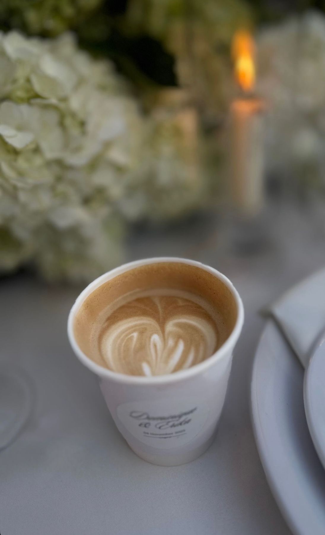 Latte with heart latte art beside white florals