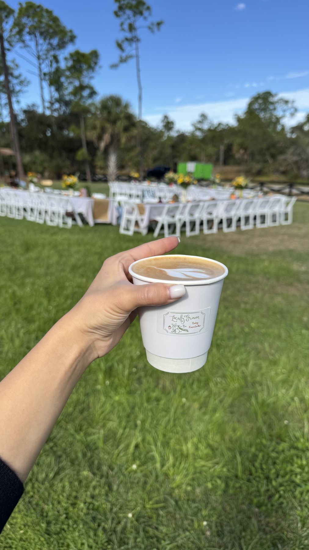 Latte held up on the lawn at an outdoor wedding